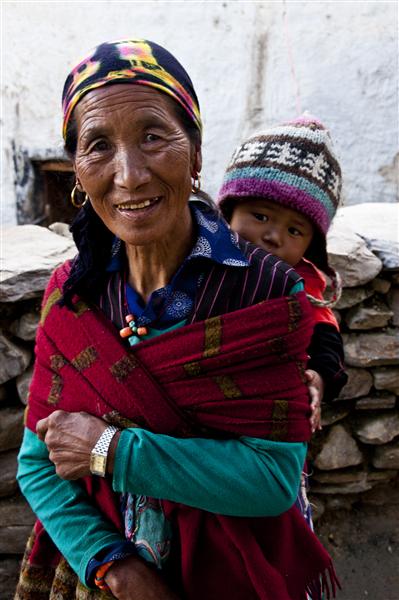 A grandmother holds walk pass the village, holding her grandson in traditional style.
