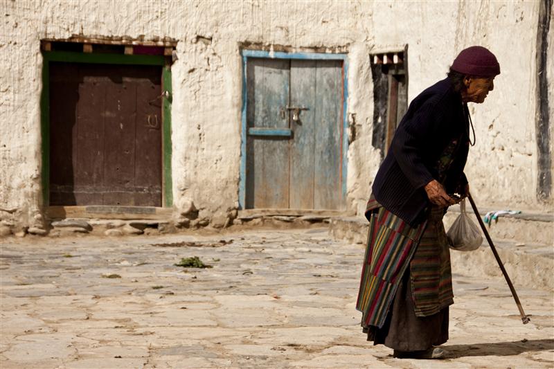 An elderly woman  is seeing outside her house in Upper Mustang