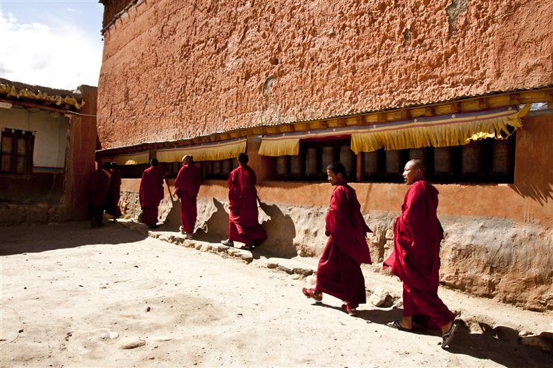 Buddhist monks do the kora, a religious walk alongside the monastery in Tsarang, Upper Mustang