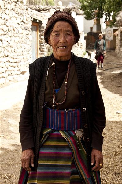 Loba woman in traditional dress stops for a picture while having a walk in the village.