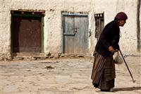 An elderly woman  is seeing outside her house in Upper Mustang