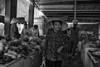 An elderly Vietnamese woman makes her way through a local produce market