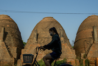 A girl rides her bicycle past one of Sa Dec's brick kilns